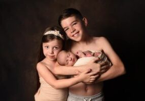 boy and girl holding newborn baby