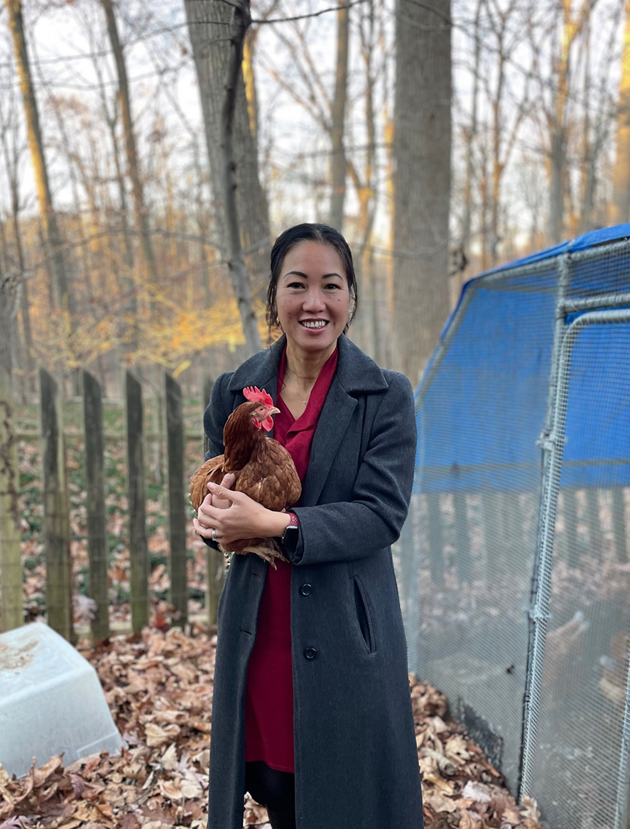 Chemistry teacher Hoa Cost poses with one of her family's chickens in December, 2023.