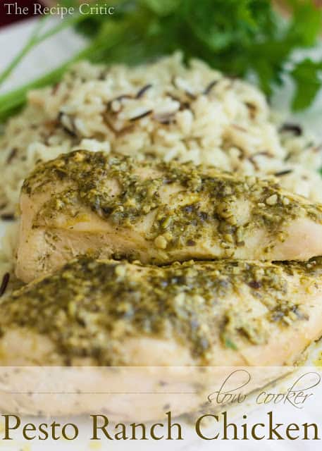 Two slow cooker chicken pesto chicken pieces on a white plate with rice and green garnish.