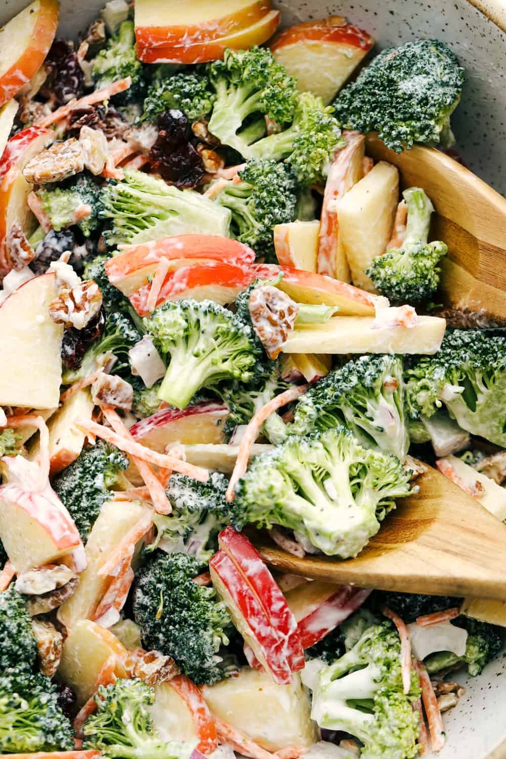 Upclose picture of broccoli apple salad with pecans, raisins and dressing. 