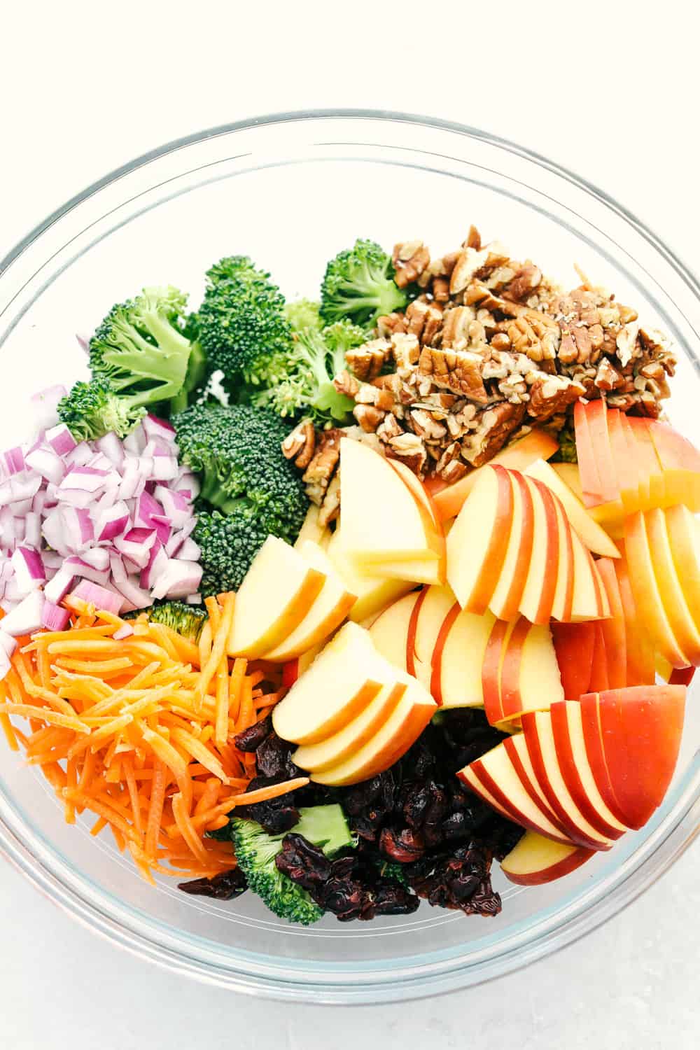 The ingredients to make broccoli apple salad in a bowl ready to combine. 