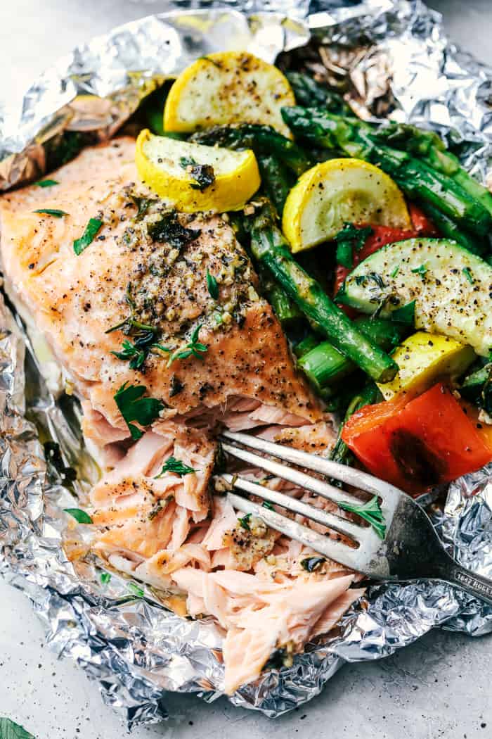 Butter Garlic Herb Salmon Foil Packets with a fork pulling the salmon apart.