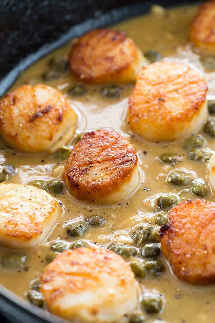 Golden brown scallops sitting in a lemon caper sauce