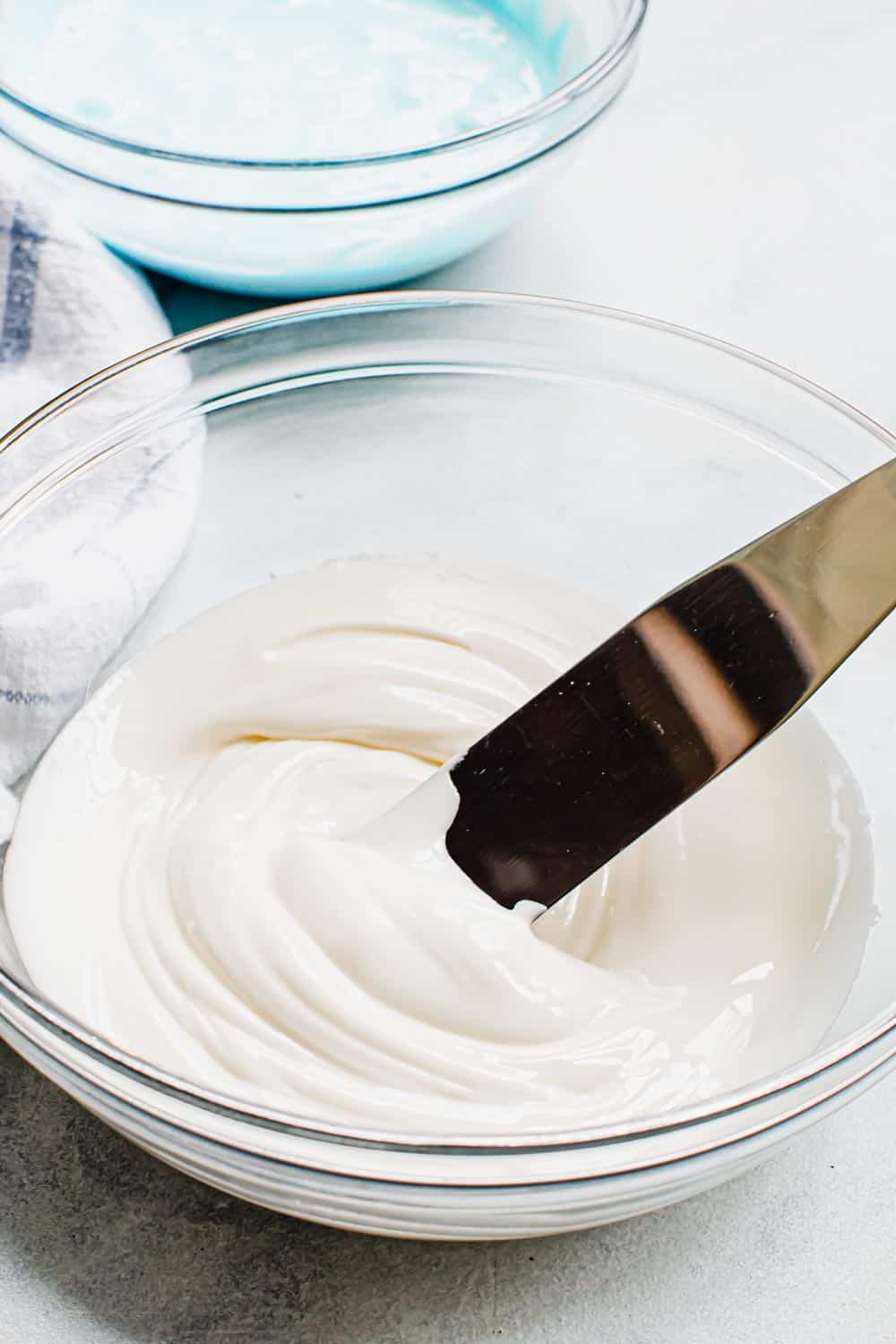 Royal icing in a glass bowl with a spreader.