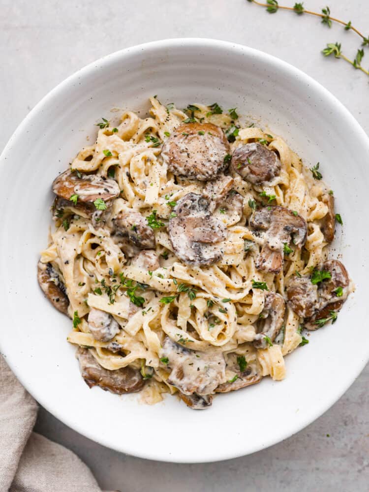 Pasta coated with mushroom sauce, served in a white bowl.