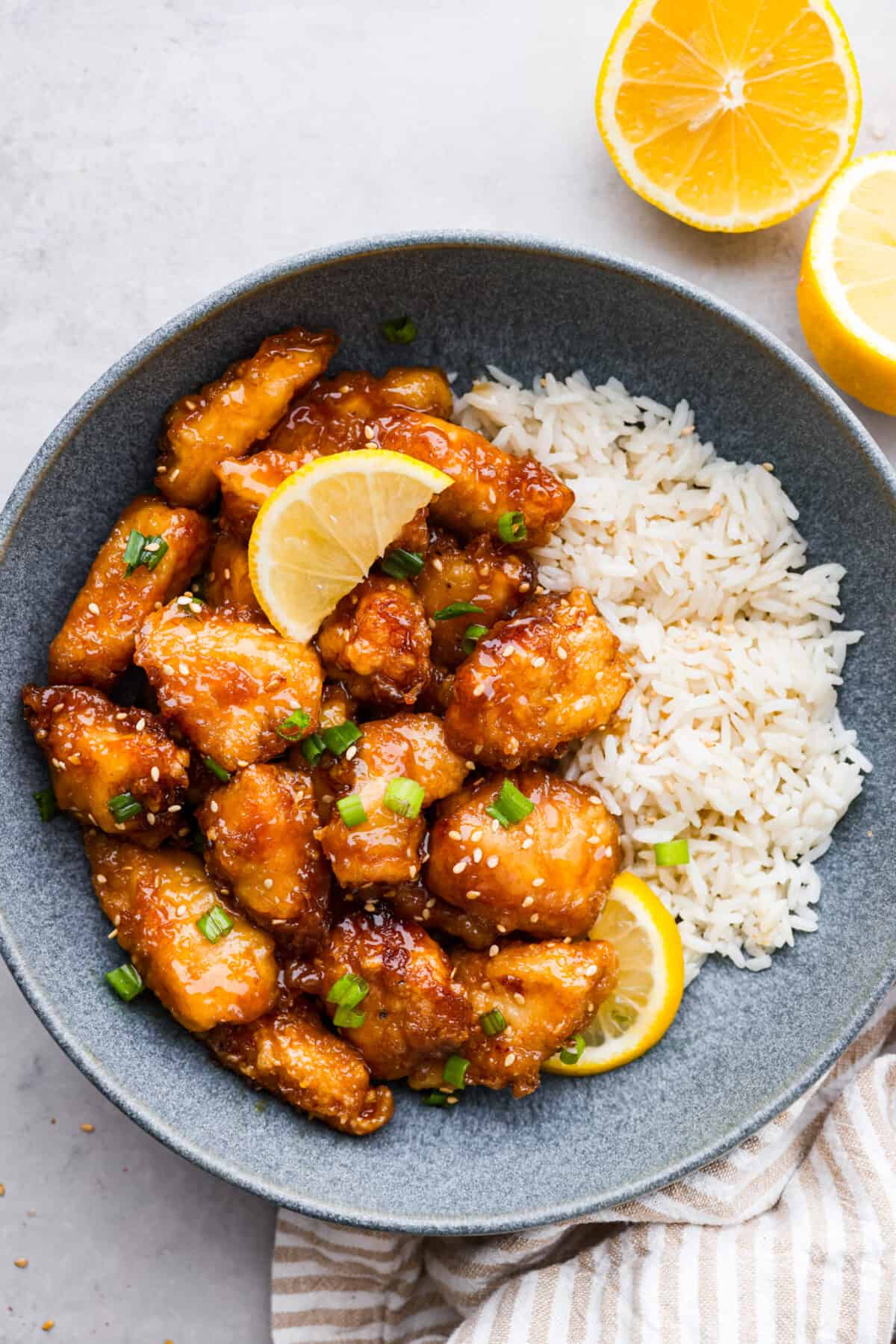 Lemon chicken served with rice in a gray stoneware bowl.