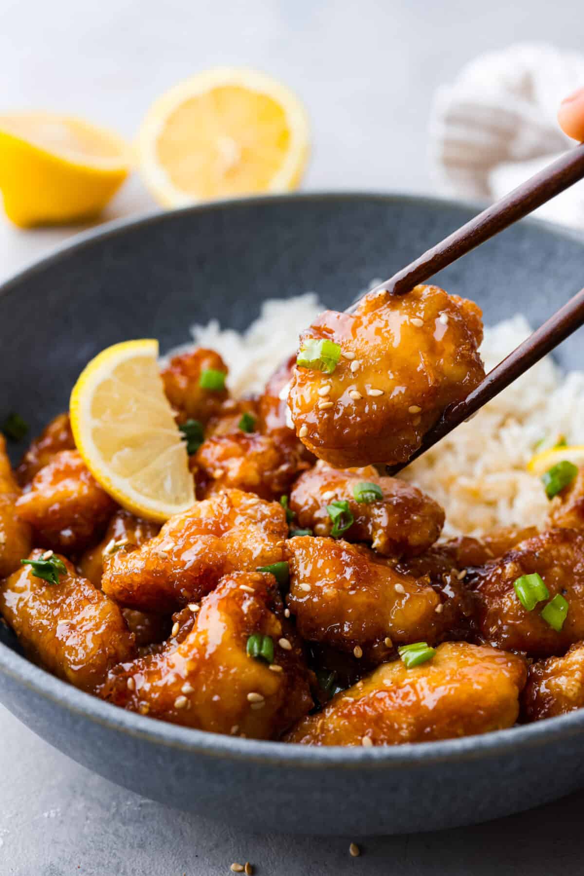 A piece of chicken being picked up with chopsticks.