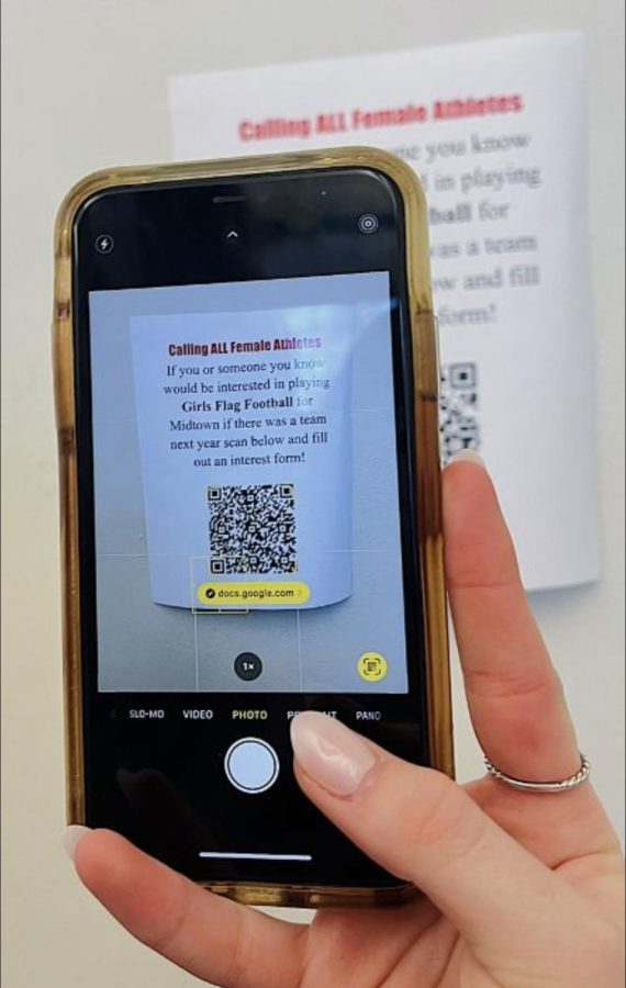 Sophomore Caitlin Stanley and Junior Chloe Walker put up flyers with a scannable QR code to gauge interest in a girl's flag football team at Midtown. 