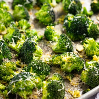 Close up view of roasted broccoli on a baking sheet.