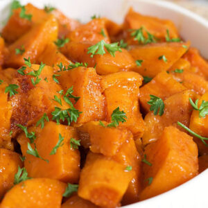 Candied yams close up in a white bowl.