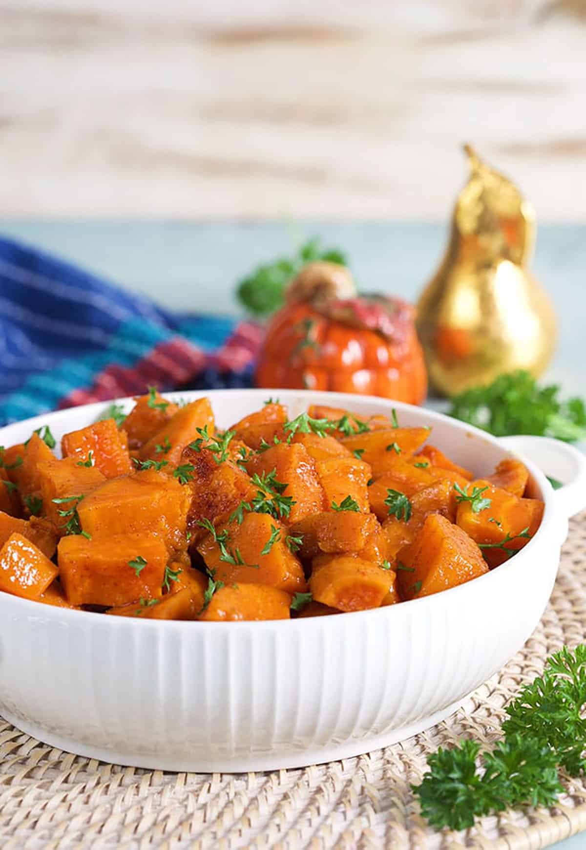 Candied yams in a white serving dish on a wicker placemat.