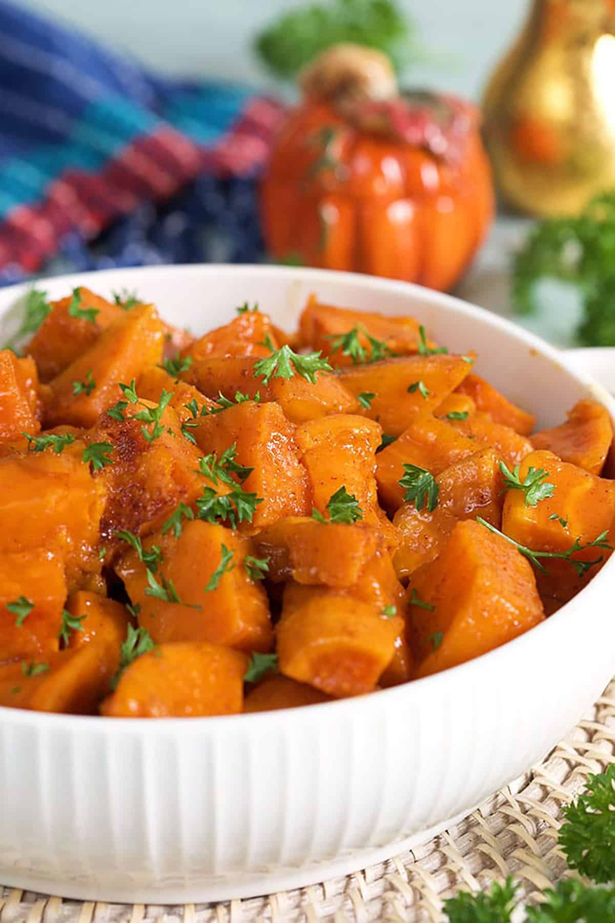 Candied Yams in a white serving bowl on a blue background.