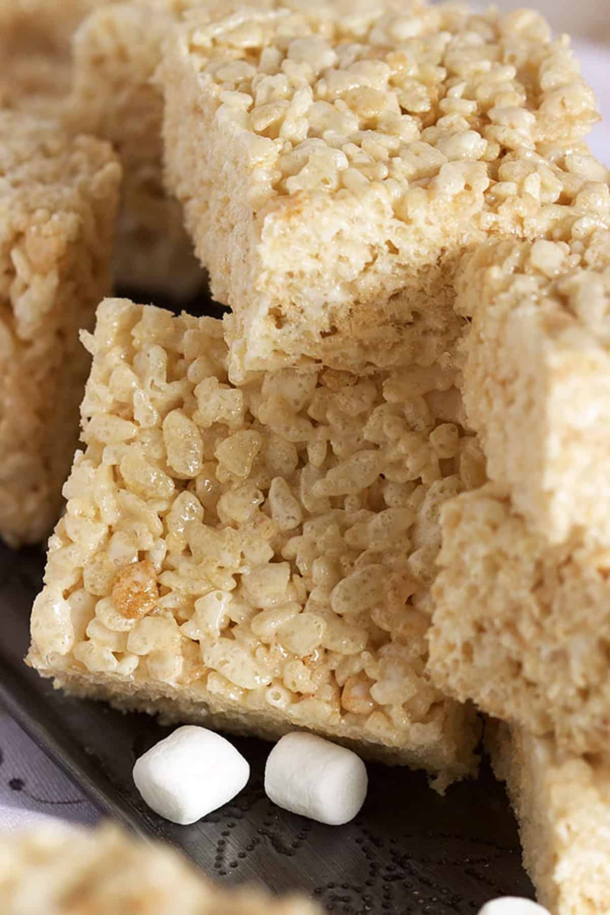 Pile of Rice Crispy Treats on a metal tray with mini marshmallows.