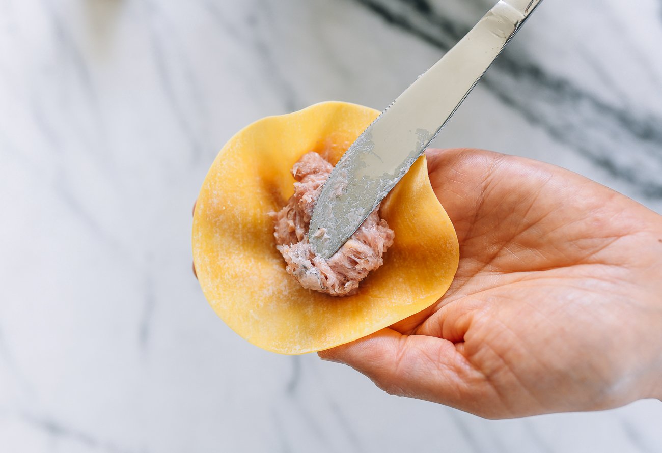 using butter knife to put siu mai filling on wrapper