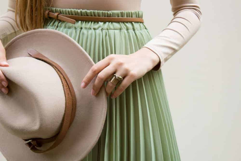 Woman with green gathered skirt and a beige hat.