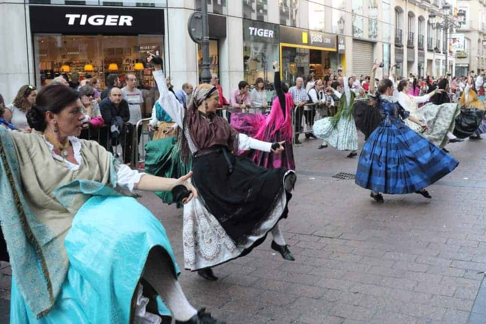 Women in peasant skirts dancing during a parade.