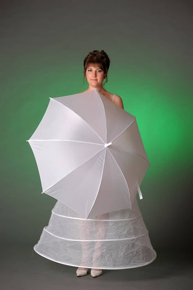 Woman in a white petticoat holding an umbrella.