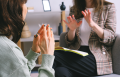 two women sitting holding hands up