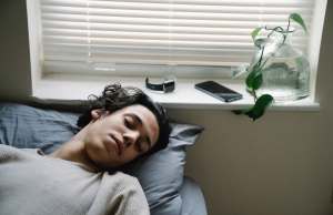 youngster-sleeping-near-gadgets-in-bedroom