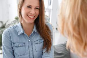 Woman in a denim shirt smiling at her therapist as they discuss ADHD