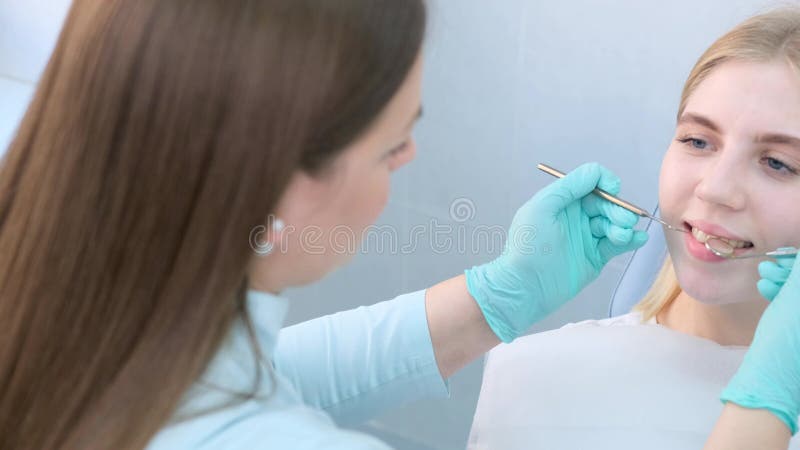 Dentist Conducting a Routine Dental Check-Up on Female Patient in ...