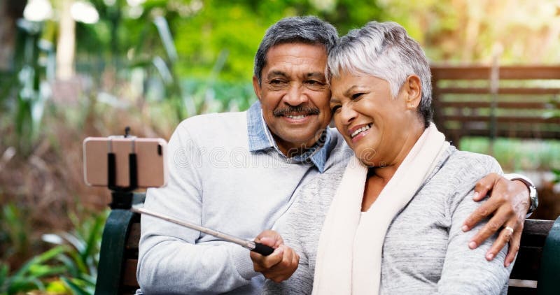 We still look as good as ever. an affectionate senior couple using a cellphone to take a selfie together in the park. stock images