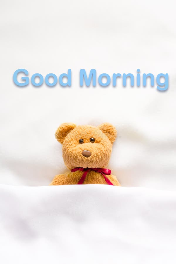 Teddy Bear lying in the white bed with message ' Good morning ' stock photography