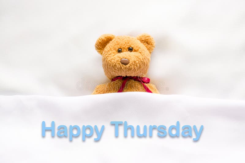 Teddy Bear lying in the white bed with message Happy Thursday stock photos