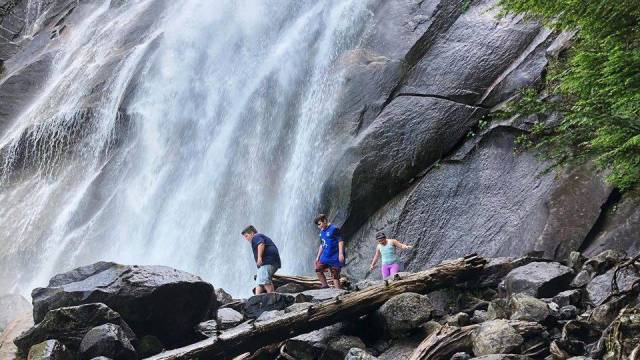 Seattle waterfall hikes include bridal veil falls where kids cross a fallen log with the waterfall in the distance