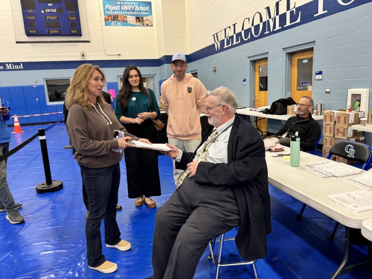 Brenda Towne (left) hands challenge submission to Election moderator Chris Regan (center right) 