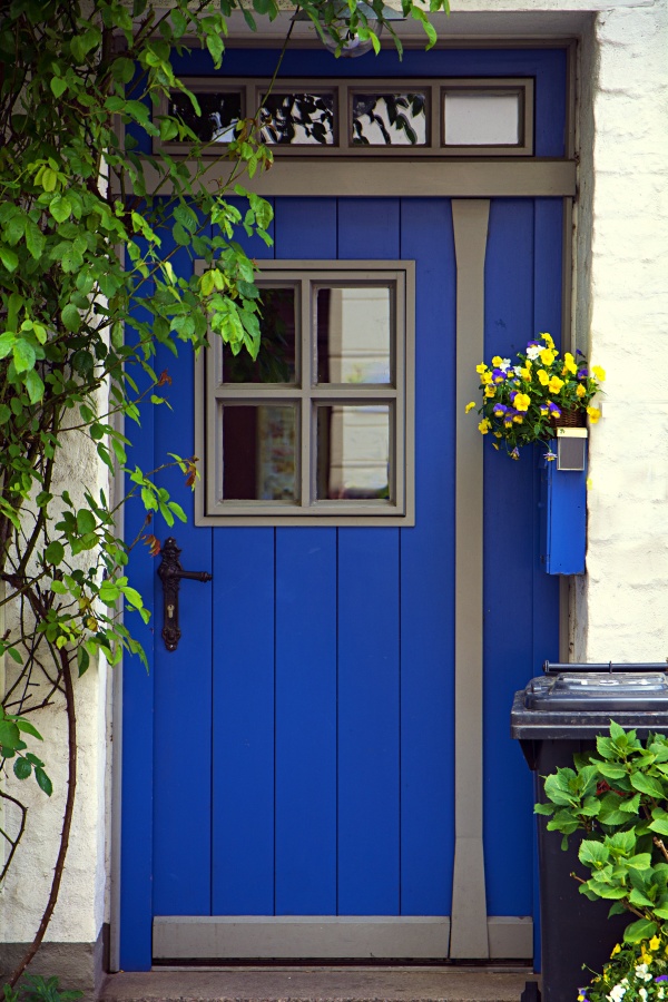 beautiful blue front door with windows in a white painted brick wall and climbing plants in the historic old town of Luebeck, Germany