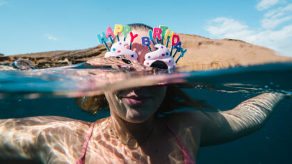 a person swimming with happy birthday glasses on