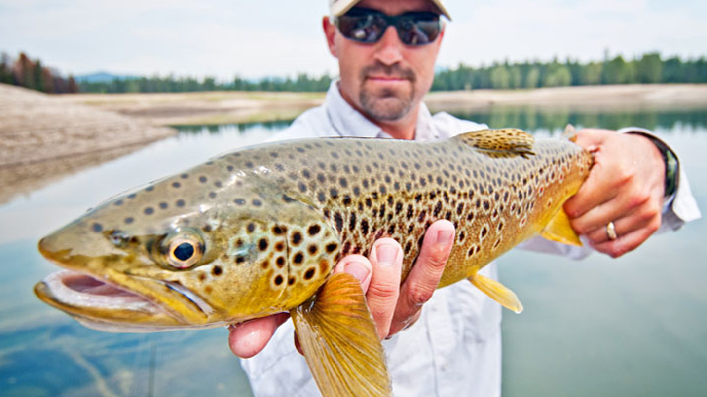 A man holds a large fish up to the camera