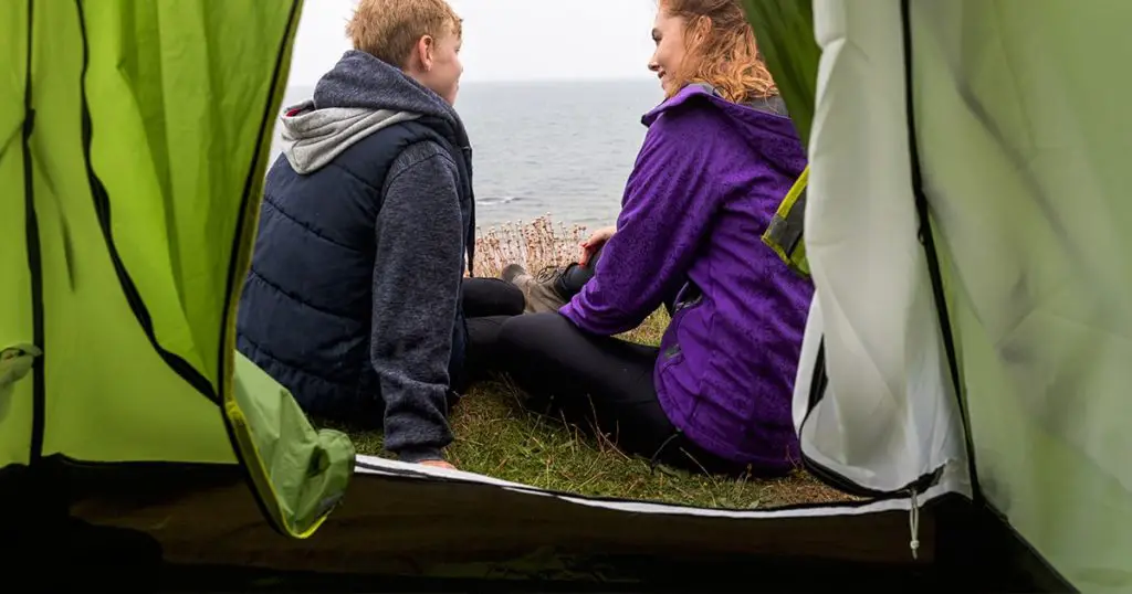 Boy and woman talking, view from inside a tent