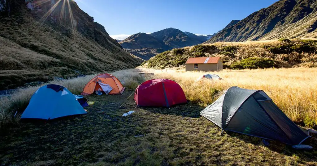 Sun strikes ridge above Top Waitaha Hut with tents