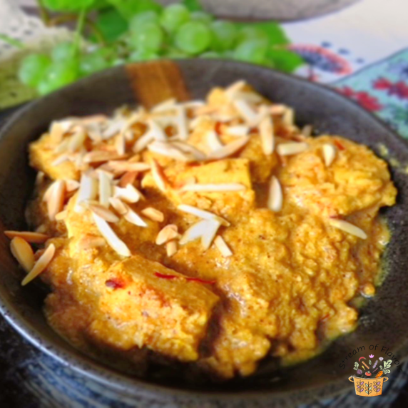 Chicken Pasanda with almond gravy topped with saffron and slivered almonds in a black bowl