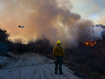 A firefighter watches a helicopter fight a wildfire