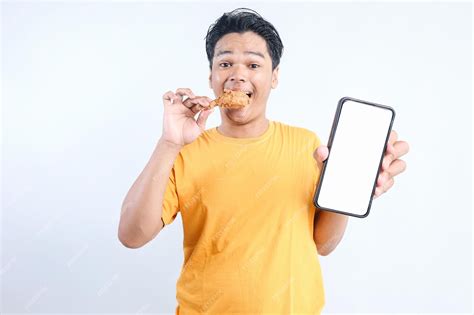 Premium Photo | Young Asian man eating fried chicken while showing ...