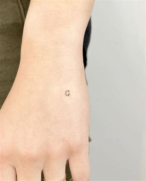 Minimalist letter "G" tattoo on the hand.