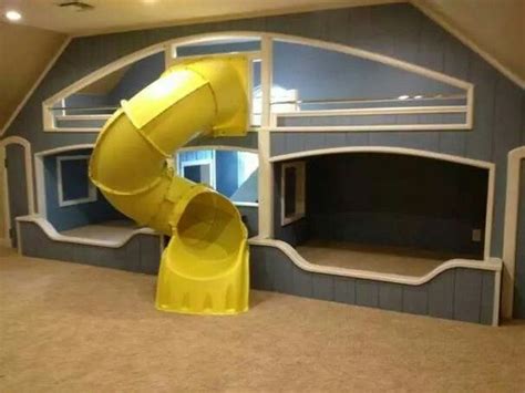 a large yellow slide is in the middle of a room with gray walls and carpet