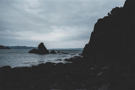 Rocky cliff in sea washing sandy beach · Free Stock Photo