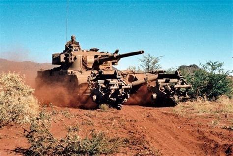 an army tank driving down a dirt road