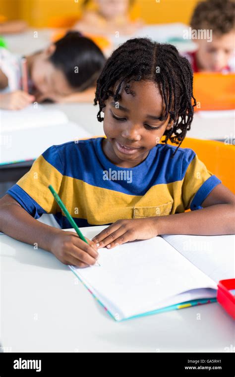 Cute boy writing on book Stock Photo - Alamy