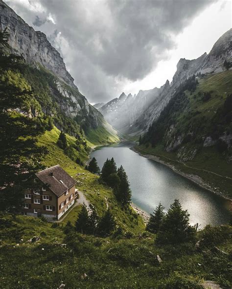 a house on the side of a mountain next to a lake