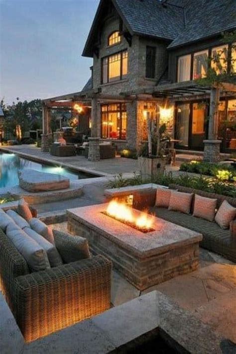 an outdoor fire pit in front of a large house with a pool and patio ...