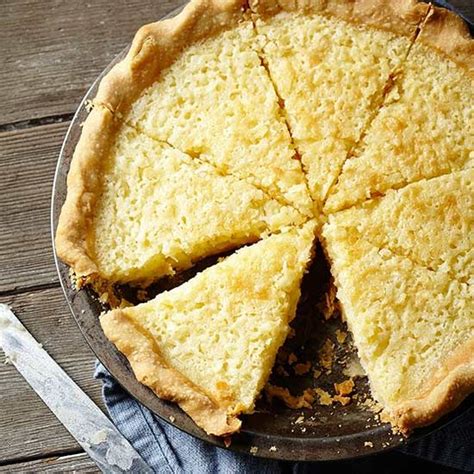 a pie sitting on top of a metal pan next to a knife and spoons