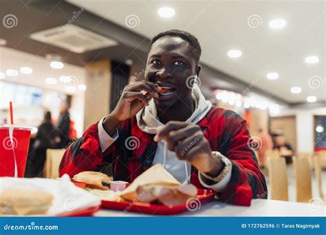 African Man is Eating Chicken Nuggets in a Restaurant and Enjoying ...