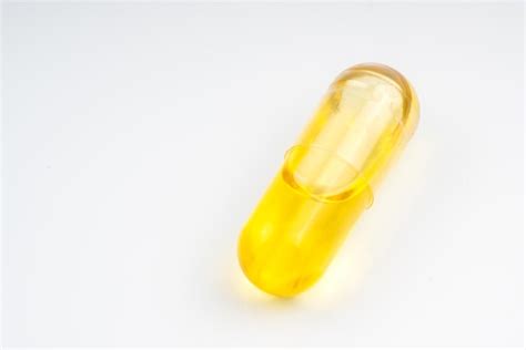 Premium Photo | Close-up of yellow capsule against white background