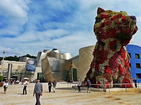 people are walking around in front of a building with flowers on the ...