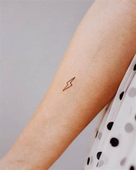 Minimalist lightning bolt tattoo on the inner forearm.